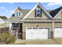 Charming exterior showcasing a two-car garage, stone accents, neutral siding, and classic architectural details under a bright blue sky at 78 Radcliffe Ct, Clayton, NC 27527