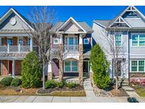 Charming two-story townhome featuring a covered front porch with stone accents and a balcony at 966 Shoofly Path, Apex, NC 27502