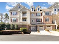 Three-story home featuring garages, multiple windows, dormers, neutral colors, and a balcony on a sunny day at 10411 Rosegate Ct # 202, Raleigh, NC 27617