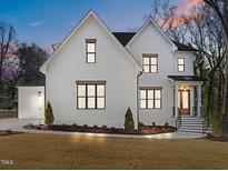 Elegant white brick home boasts a manicured lawn and inviting front entrance with a black awning and wood door at 1318 Ivy Ln, Raleigh, NC 27609