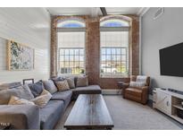 Bright living room with exposed brick, large windows, and comfortable seating at 1535 Caraleigh Mills Ct # 105, Raleigh, NC 27603