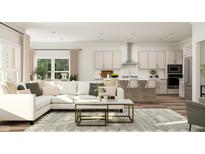 An open living room and kitchen area with a white sectional couch and kitchen island with seating for three at 1569 Goldfinch Perch Ln, Knightdale, NC 27545