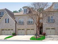 Elegant townhome featuring a brick facade, multiple garage bays, and Juliet balconies on the second floor at 162 Arabella Ct, Cary, NC 27518