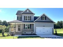 Charming two-story home features a covered porch, manicured lawn, and a two car garage at 169 Tigris Ct, Zebulon, NC 27597