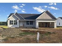 Charming single-Gathering home featuring a spacious two-car garage and stylish gray siding, set under a bright blue sky at 207 N Movado Trl, Kenly, NC 27542