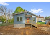 Charming blue home with a cozy front porch and freshly landscaped yard, providing curb appeal at 230 N Melville St, Graham, NC 27253