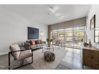 Bright living room with concrete floors, neutral palette, and large window at 319 Fayetteville St # 207, Raleigh, NC 27601