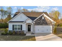 Charming single-Gathering home featuring stone accents, a black front door with wreath, and a well-maintained lawn at 75 Red Crabapple Ct, Clayton, NC 27520