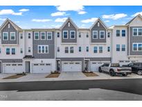 Charming townhomes with white siding, gray accents, garages, and well-maintained landscaping on a sunny day at 818 Lilyquist Way, Wake Forest, NC 27587