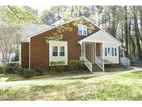 Charming brick home with cream trim, a cozy front porch, and manicured front lawn at 8310 Wycombe Ln, Raleigh, NC 27615