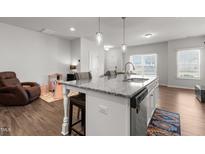 Bright kitchen featuring granite countertops, stainless steel appliances, and a stylish island with pendant lighting at 1805 Kauri Cliffs Dr, Fuquay Varina, NC 27526