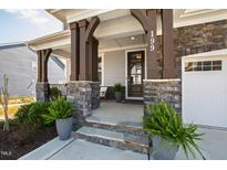 Inviting front porch with stone accents, stylish columns, and well-manicured landscaping offers curb appeal at 199 High Woods Rdg, Chapel Hill, NC 27517