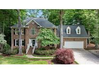 Charming brick home with a two-car garage, manicured lawn, and mature trees at 306 Lochside Dr, Cary, NC 27518