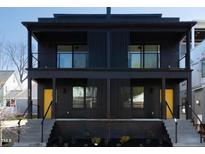 Modern black townhouse with two stories, balconies, black railings, and bright yellow doors at 409 Alston St # 101, Raleigh, NC 27601