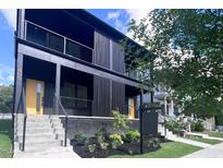 Modern home showcasing black vertical siding, yellow door, and sleek landscaping at 409 Alston St # 102, Raleigh, NC 27601