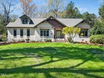 Charming brick home featuring a well-manicured lawn, mature trees, and a welcoming entryway at 5512 Deer Hunter Ct, Garner, NC 27529