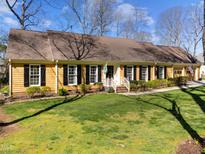 Charming yellow home with black shutters, manicured lawn, and welcoming front porch at 7021 Cedar Bend Ct, Raleigh, NC 27612