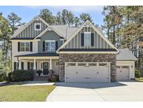 Charming two-story home featuring a stone facade, well-manicured lawn, and a three car garage at 1033 Jensen Grove Ct, Fuquay Varina, NC 27526