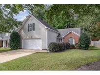 Charming home featuring a two-car garage, brick accents, lush landscaping, and mature trees at 110 Brierridge Dr, Apex, NC 27502