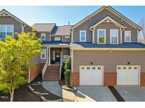 Charming townhome featuring brick accents, a two-car garage, and inviting front porch at 11003 Louson Pl, Raleigh, NC 27614