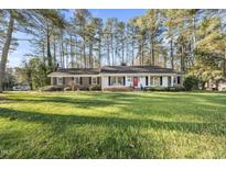 Charming ranch-style home with brick and siding exterior, red front door, and a lush green lawn at 11801 Strickland Rd, Raleigh, NC 27613