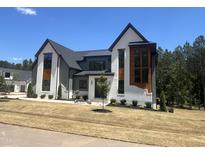 Stunning two-story home with modern design, dark windows, gray and white brick, and a well-manicured lawn at 170 Cherry Bark Dr, Youngsville, NC 27596
