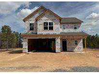 Unfinished two-story home with visible framing and a two-car garage, set on a spacious lot surrounded by trees at 228 Dove Rd, Cameron, NC 28326