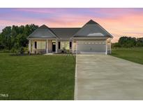Charming single-Gathering home featuring a well-manicured lawn, long driveway, and attached two-car garage at 4013 Kingcraig Ln, Zebulon, NC 27597