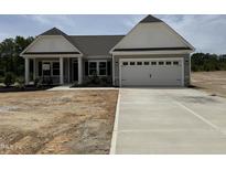 Charming single-story home featuring a two-car garage, gray siding, and manicured landscaping at 4013 Kingcraig Ln, Zebulon, NC 27597