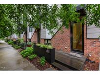 Modern townhome featuring brick and steel exterior with wood porch and landscaped planter at 402 Chavis Way, Raleigh, NC 27601