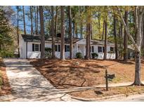 Charming white brick home with black shutters and a well-maintained yard and mature trees at 5812 Timber Ridge Dr, Raleigh, NC 27609