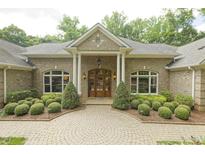 Stately brick home featuring a beautiful entrance with manicured landscaping and a circular driveway at 6452 Therfield Dr, Raleigh, NC 27614