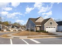 Charming gray home featuring an attached two-car garage and manicured lawn on a tree-lined street at 101 Maroon Ct, Raleigh, NC 27610
