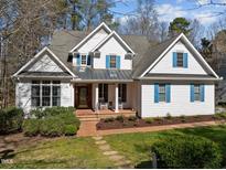 Traditional home with white siding, blue shutters, covered porch, brick walkway, and lush landscaping at 108 Ironwoods Drive Dr, Chapel Hill, NC 27516