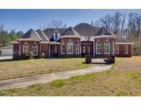 Elegant brick home featuring arched windows, dormers, and a landscaped walkway leading to the entrance at 119 Cardinal Crest Ct, Pittsboro, NC 27312