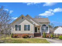 Charming one-story home with yellow siding, green shutters, brick foundation, and well-maintained landscaping at 1211 Azalea Dr, Zebulon, NC 27597