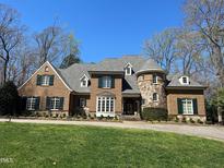 Beautiful brick home featuring manicured lawn, dormer windows, a stone turret, and dark green shutters at 2207 Oxford Rd, Raleigh, NC 27608