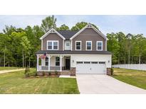 Charming two-story home with a covered front porch, attached two car garage, and a well-manicured lawn at 303 Old Fashioned Way, Lillington, NC 27546