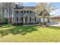 Charming two-story home with blue siding, black shutters, manicured lawn, and flowering tree at 3412 Ashmill Ct, Apex, NC 27539