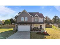 Charming two-story home with stone accents, a well-manicured lawn, and an attached two-car garage at 35 Wolf Ridge Ct, Willow Springs, NC 27592