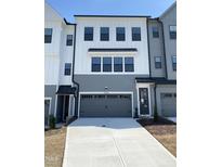 Modern townhome boasts a gray garage door, a concrete driveway and neutral paint colors at 4720 Cypress Tree Ln, Raleigh, NC 27612