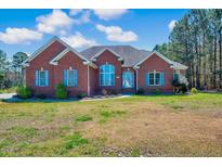 Charming red brick home with blue shutters and well-manicured front lawn under a bright sky at 7687 Mattie Rd, Rocky Mount, NC 27803