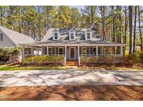 Charming Cape Cod home with a welcoming wrap-around porch surrounded by mature trees and landscaping at 7917 Blaney Franks Rd, Apex, NC 27539