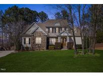 Charming two-story home with stone and siding exterior, manicured lawn and mature trees at 8704 Balbirnie Ct, Wake Forest, NC 27587