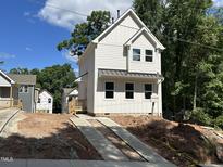 Charming new construction home featuring bright white siding, a metal roof, and a concrete driveway at 908 Colfax St, Durham, NC 27701