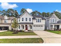 Inviting new construction two-story home with a red door, manicured lawn, and attached two car garage at 9152 Dupree Meadow Dr # 12, Angier, NC 27501
