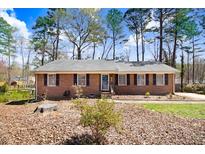 Charming brick ranch-style home with mature trees and established landscaping creating a welcoming curb appeal at 104 Amberhill Ct, Garner, NC 27529