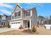 Two-story home featuring a two-car garage and a covered front porch and professional landscaping at 117 Highland Forest Dr, Fuquay Varina, NC 27526