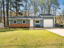 Charming blue house with brick accents, lush green lawn, and an attached single car garage at 1402 Valley Rd, Garner, NC 27529