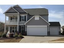 Two-story home featuring an attached garage, covered porch, and manicured landscaping at 1515 Willbrook Dr, Fuquay Varina, NC 27526